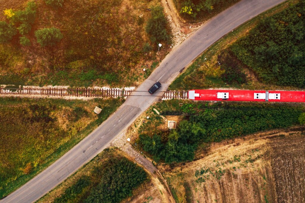 Aerial view of car and train on road junction